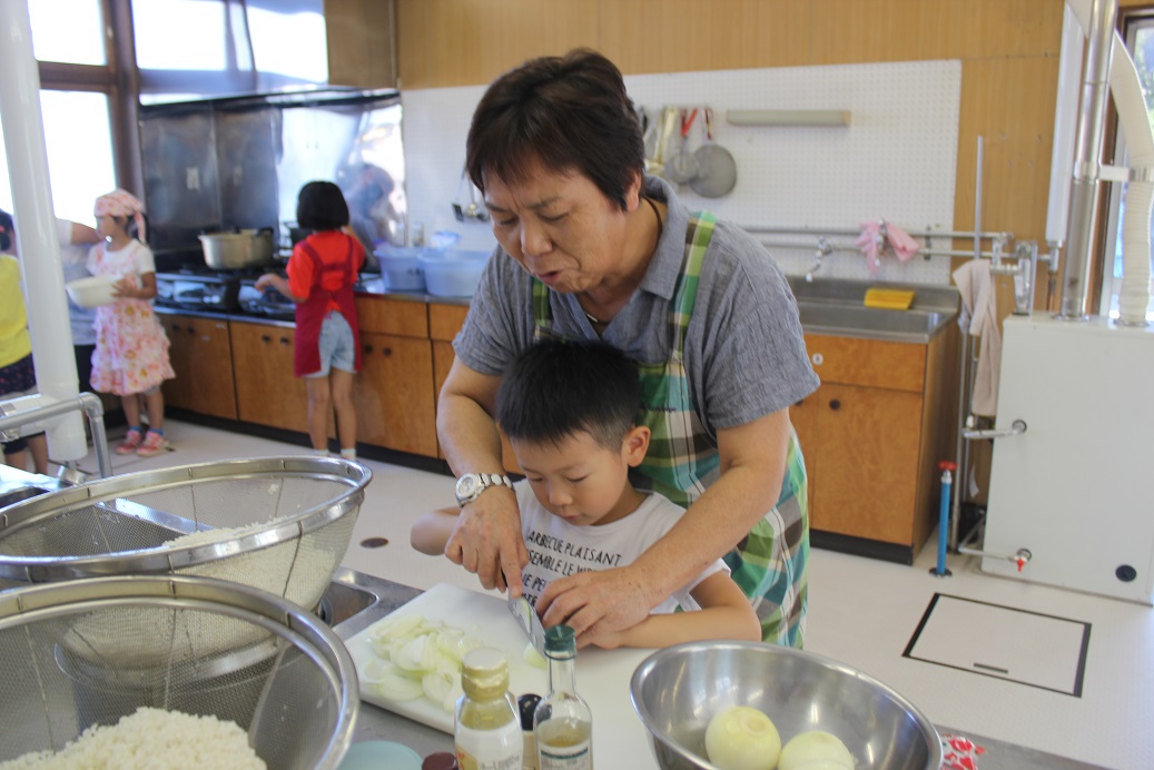 1年生の子も、手伝ってもらいながら料理します。上手く切れたかな？