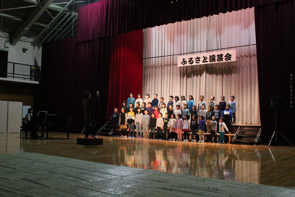 11月9日（土）島牧中学校体育館にて第18回ふるさと演芸会が開催されました。トップぺージの写真は、中学校の先生と生徒によるクラリネット・ピアノのアンサンブルの様子です。こちらは小学生の全校合唱の様子です。トップバッターで緊張したかと思いますが、大きな声で歌っていました。